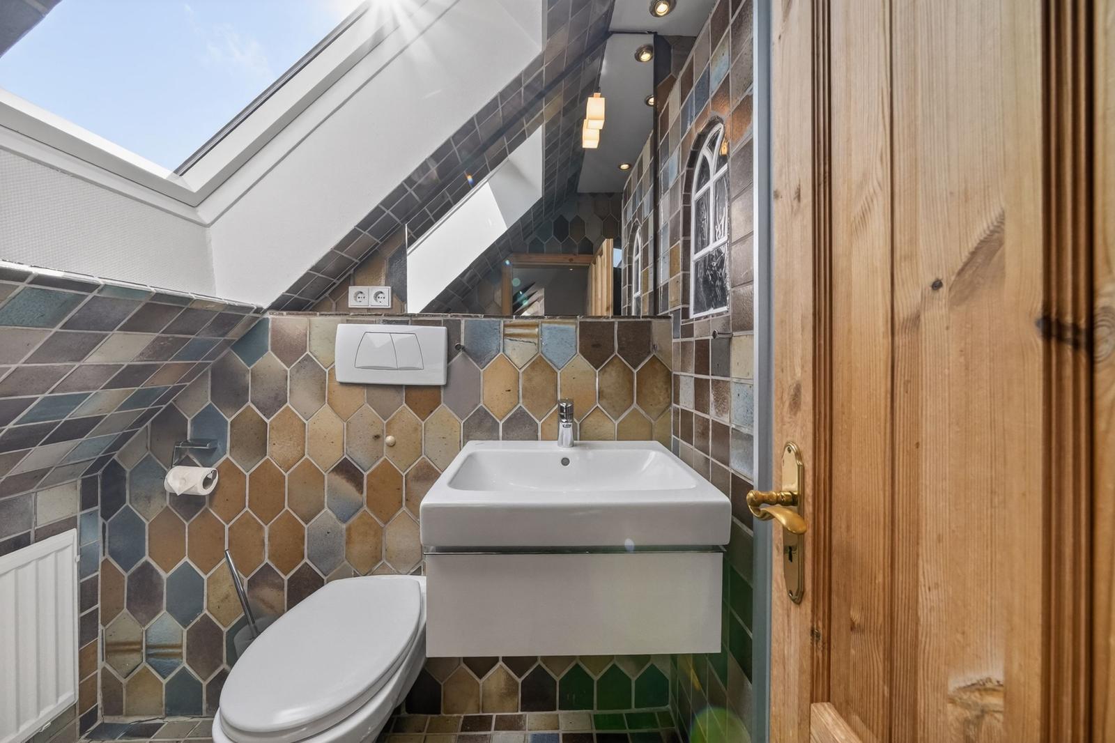 Badezimmer mit Dachfenster, sechseckigen Fliesen und Spiegelschrank.