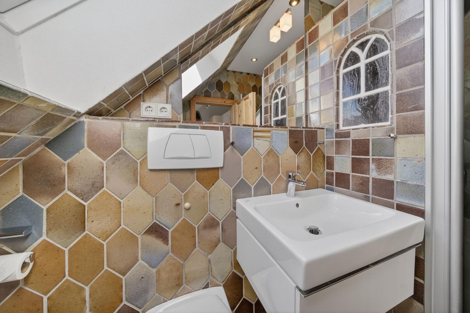 Badezimmer mit farbigen Sechseckfliesen, Waschbecken und Spiegel