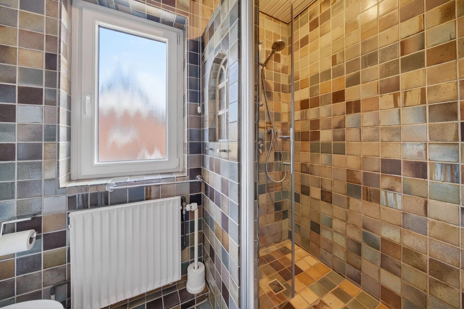 Bad mit Dusche, Fenster und Heizkörper an Wand