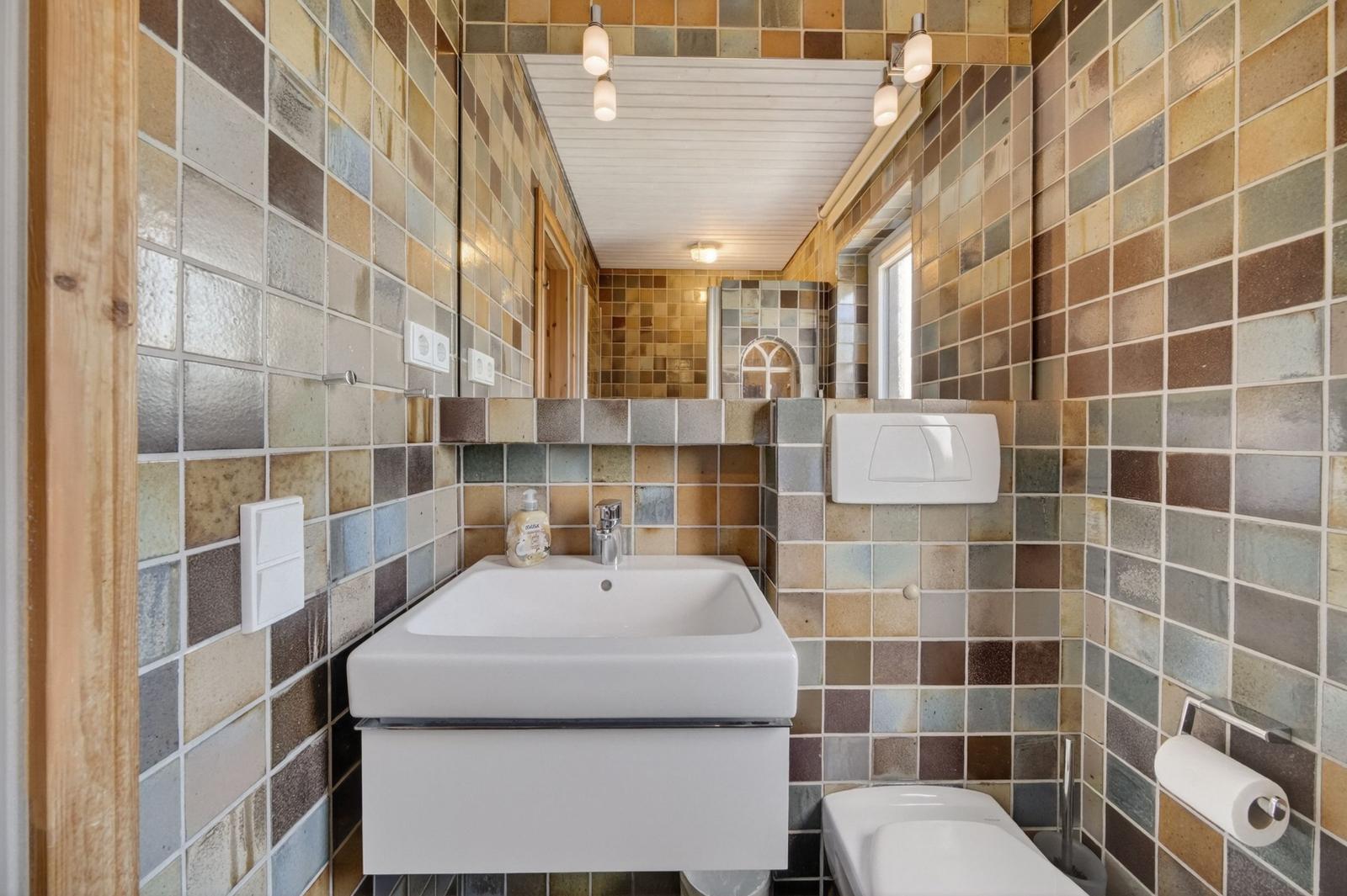Badezimmer mit farbigen Fliesen, Waschbecken und Toilette.