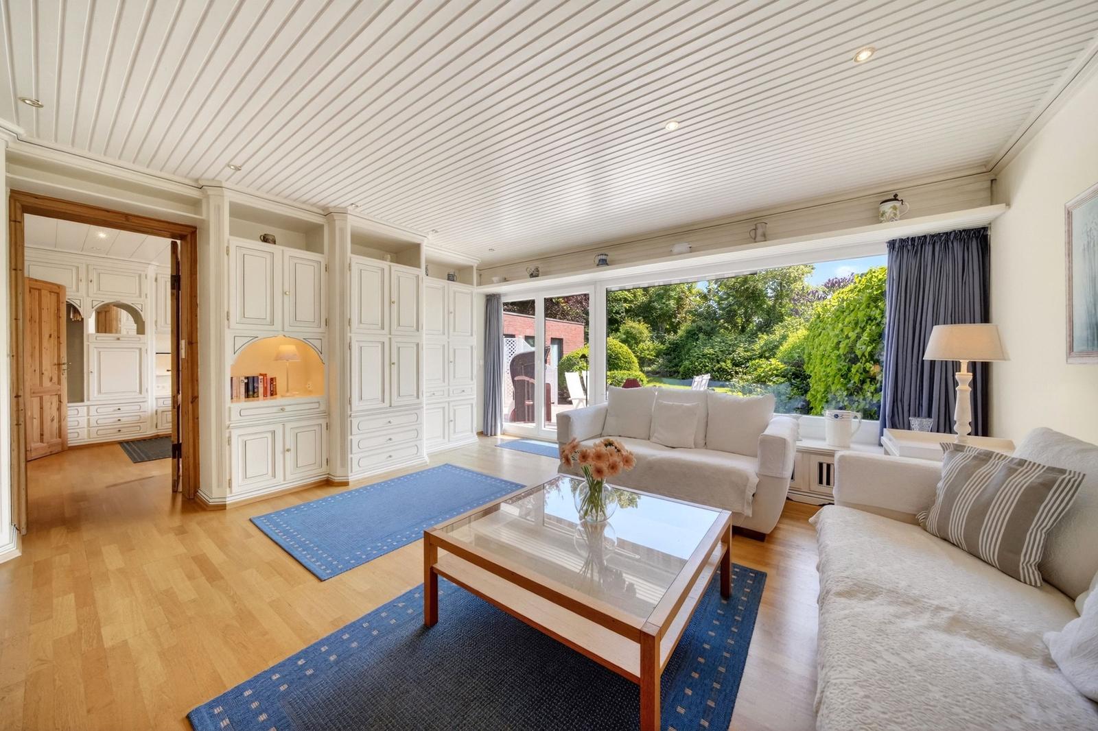 Wohnzimmer mit Sofa, Glas-Tisch und Blick auf Garten