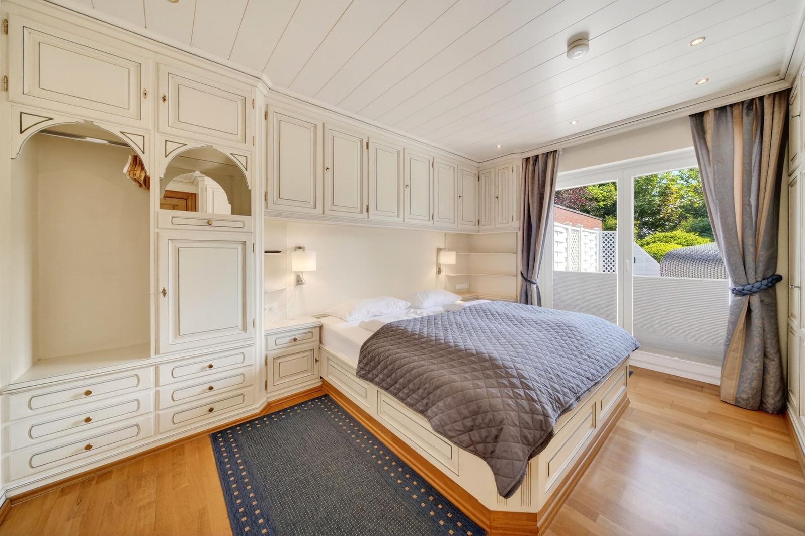 Schlafzimmer mit Bett, Schrank und Blick auf Balkon.