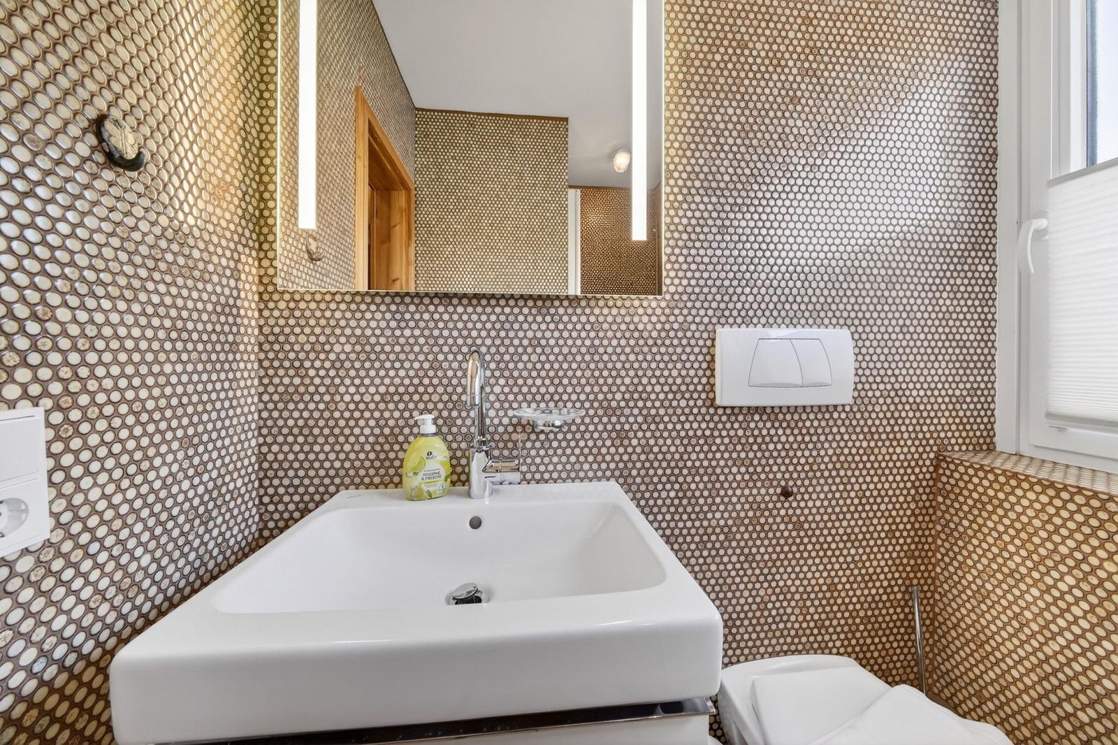 Badezimmer mit Waschbecken, Spiegel und Mosaikwand