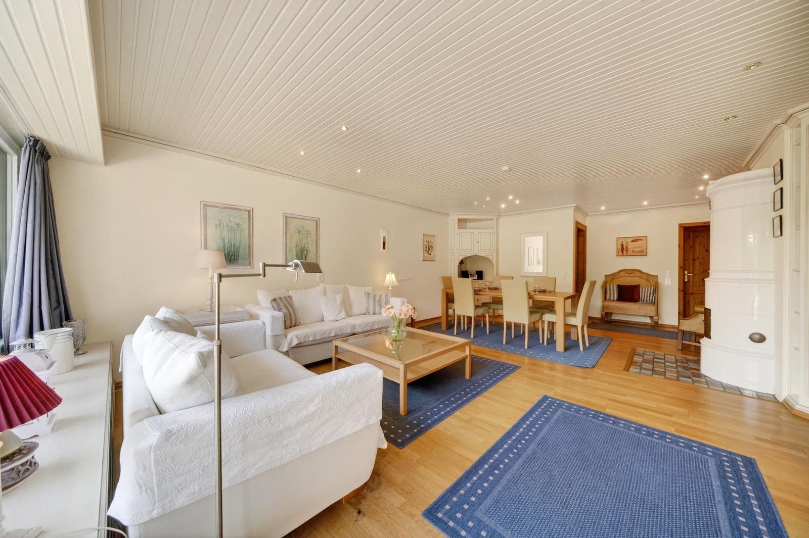 Wohn- und Essbereich mit Sofa, Tisch und Teppichen auf Holzboden.