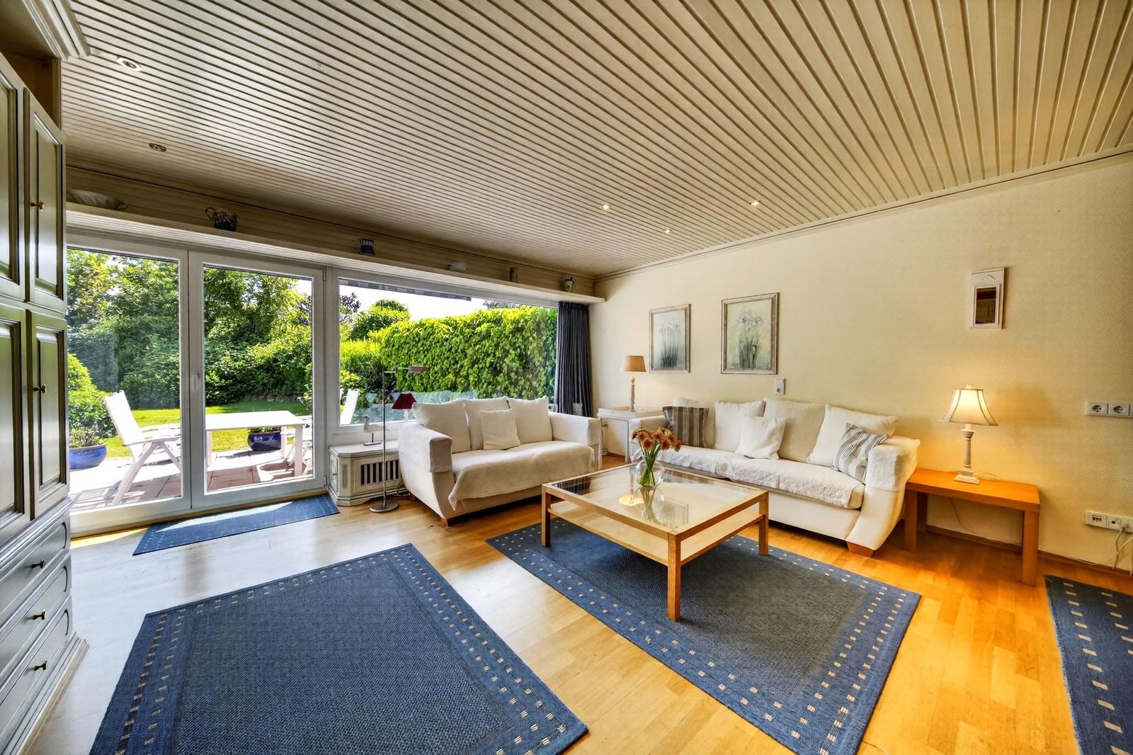 Wohnzimmer mit zwei Sofas, Glas-Tisch und Blick auf Garten.