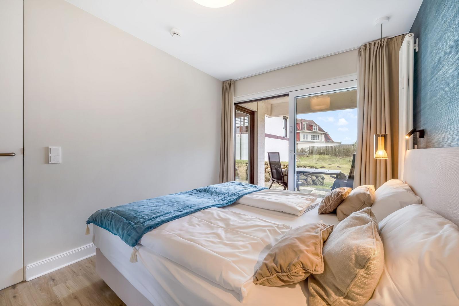 Schlafzimmer mit Bett, Fenster und Blick auf Terrasse