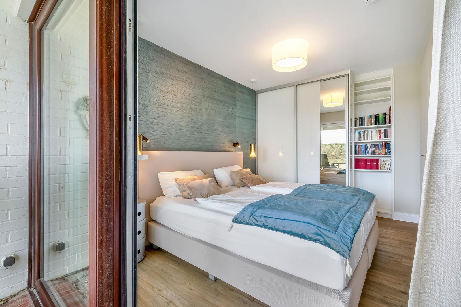 Schlafzimmer mit Doppelbett, Bücherregal und Schlafzimmermöbeln.