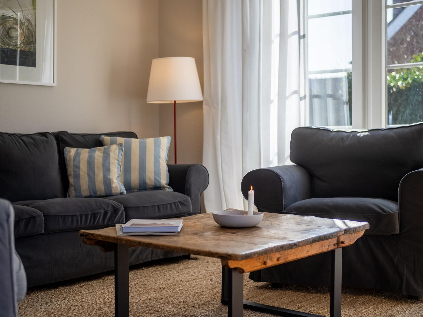 Ein Wohnzimmer mit zwei schwarzen Sofas, einem Holztisch und einem Fenster.