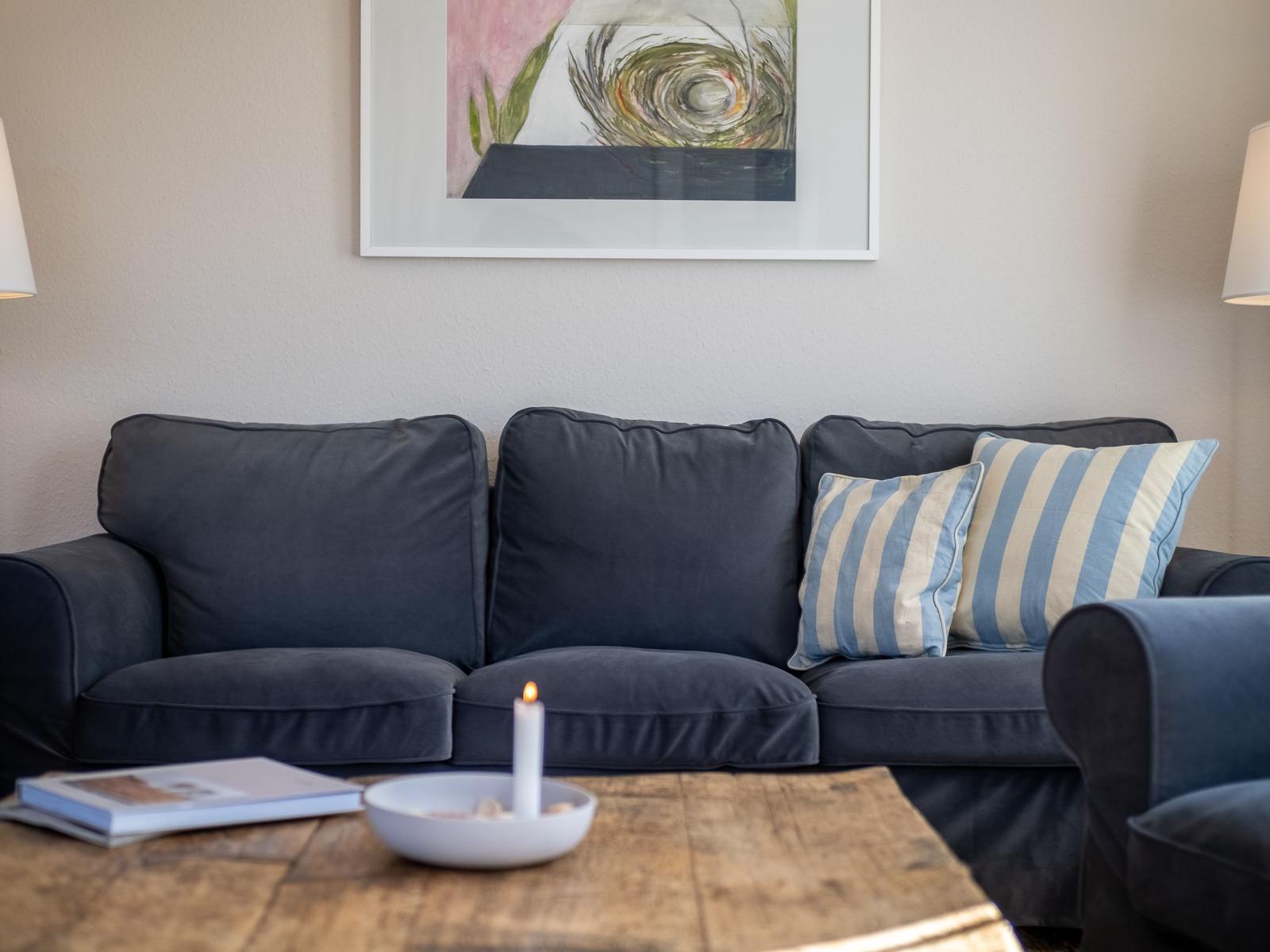 Ein Sofa mit Kissen, eine Kerze und ein Bild an der Wand.