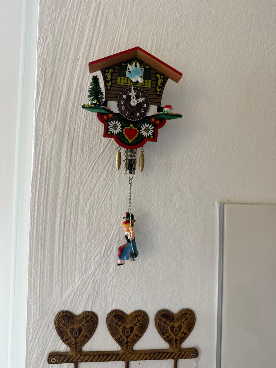 Ein deutscher Kuckucksuhr mit Figur hängt an einer Wand.