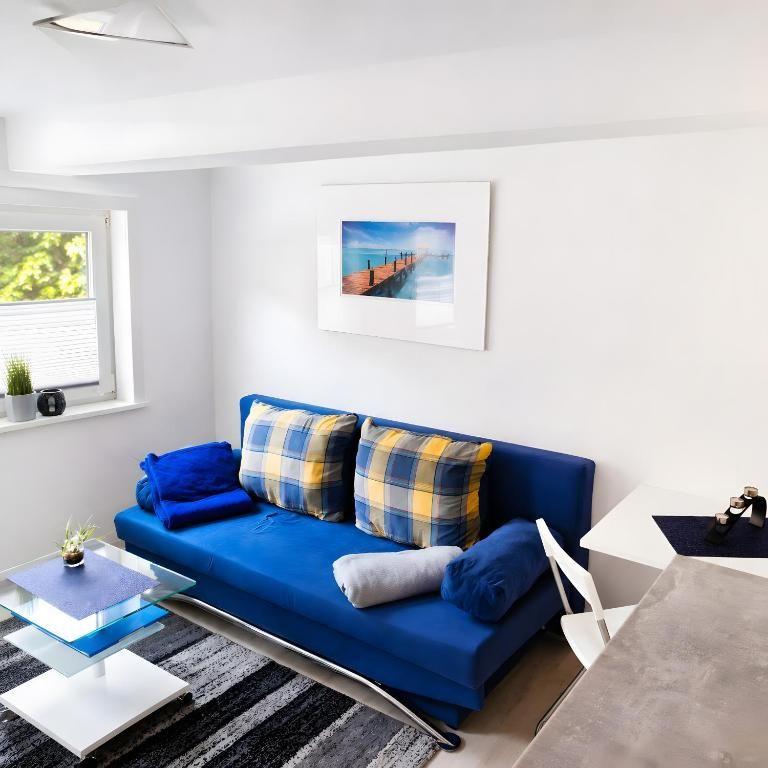 Ein Wohnbereich mit blauem Sofa, Glas-Tisch und Wandbild.