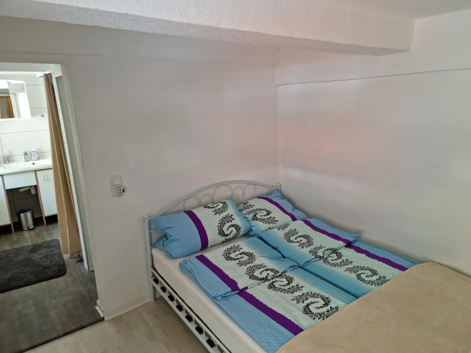 Schlafzimmer mit Doppelbett und angrenzendem Badezimmer.