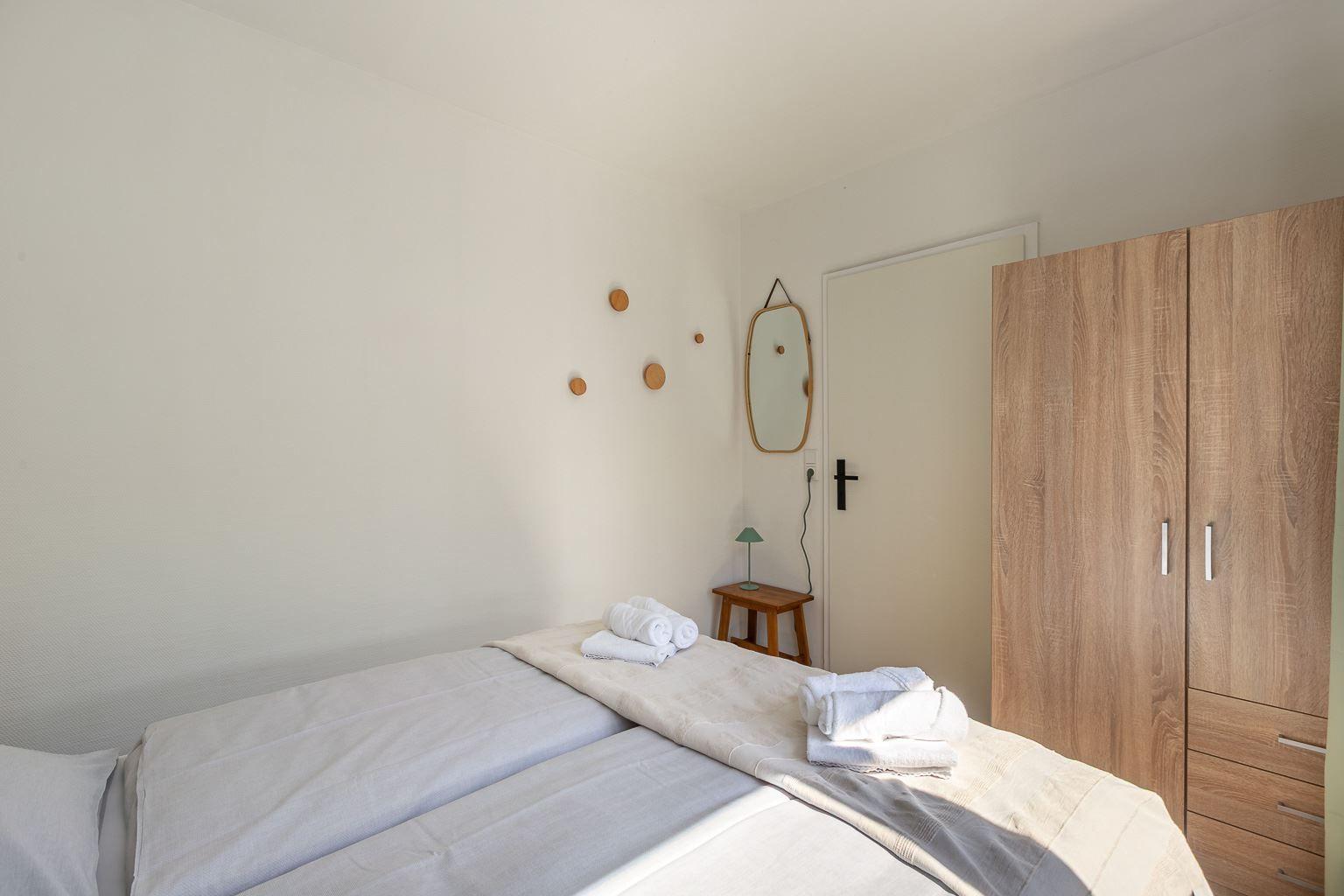 Schlafzimmer mit Bett, Kleiderschrank und Spiegel an der Wand.
