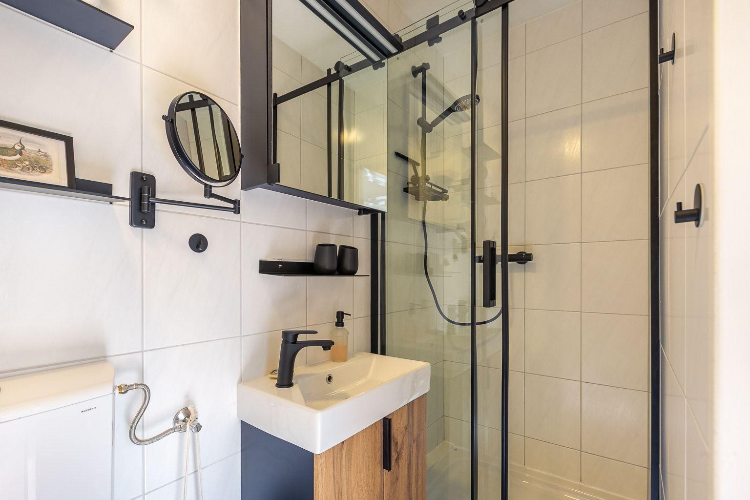 Badezimmer mit Dusche, Waschbecken und Spiegel