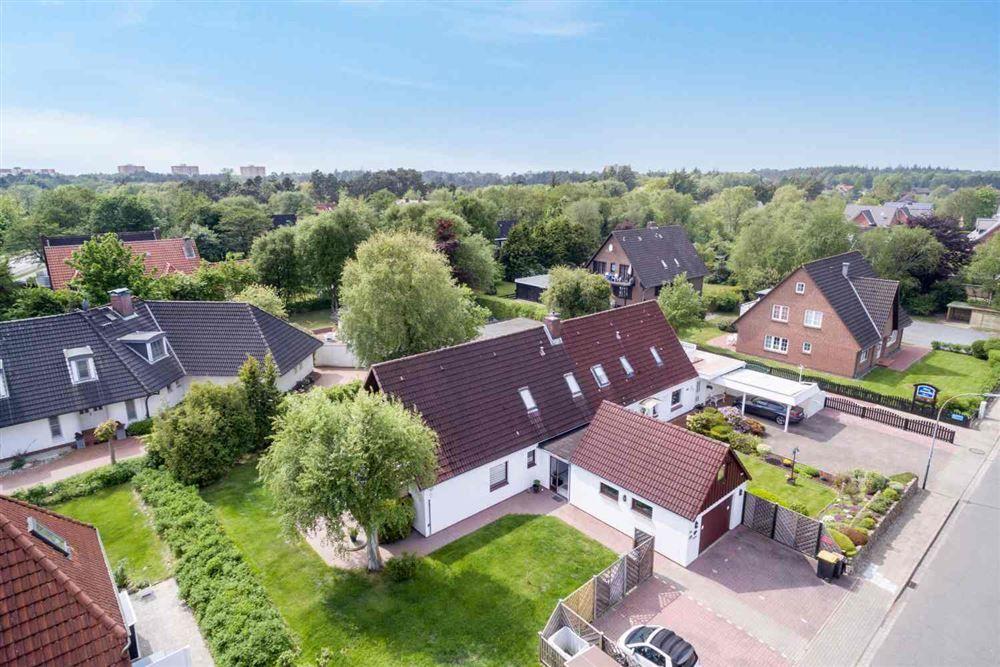 Haus mit Garten und Garage in ruhiger Wohngegend mit Blick auf Bäume und Nachbarhäuser.