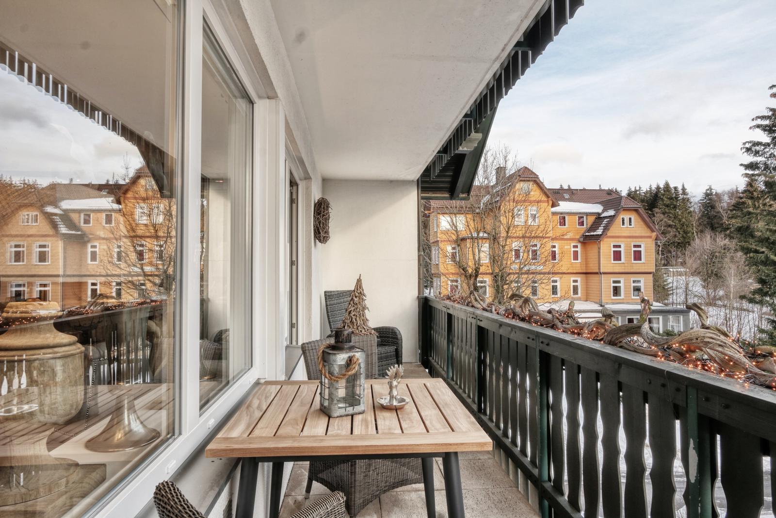 Terrasse mit Tisch und Stühlen, Blick auf gelbe Häuser und Bäume.