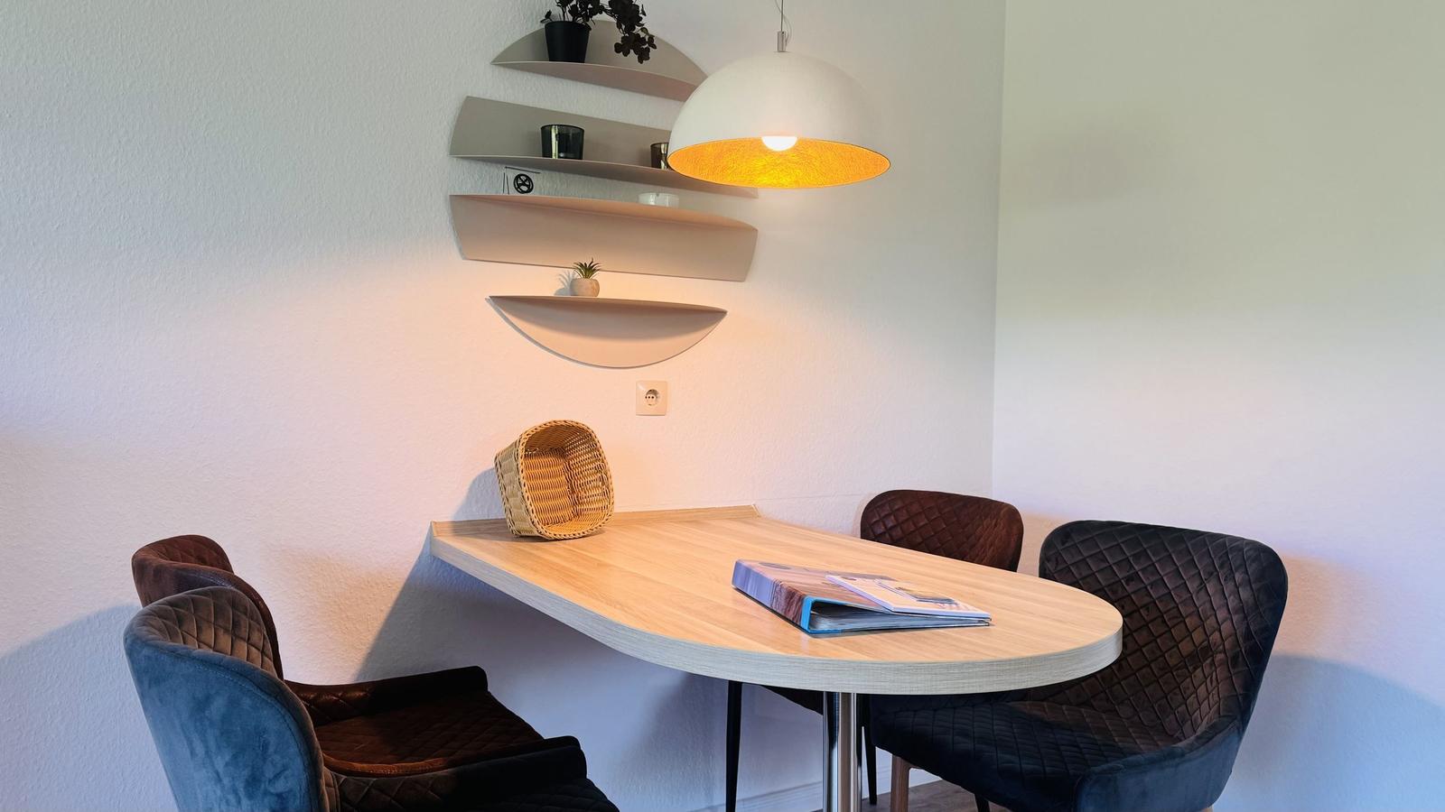 Esstisch mit vier Stühlen und Wandregalen an der Wand.