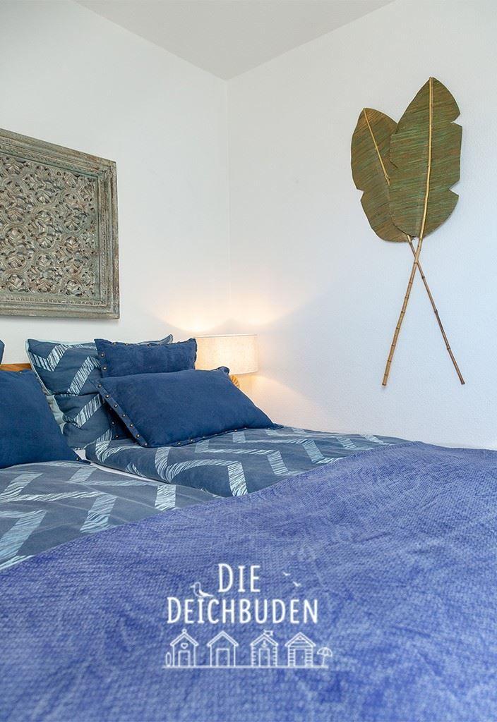Schlafzimmer mit Bett, Kissen und Wanddekoration.