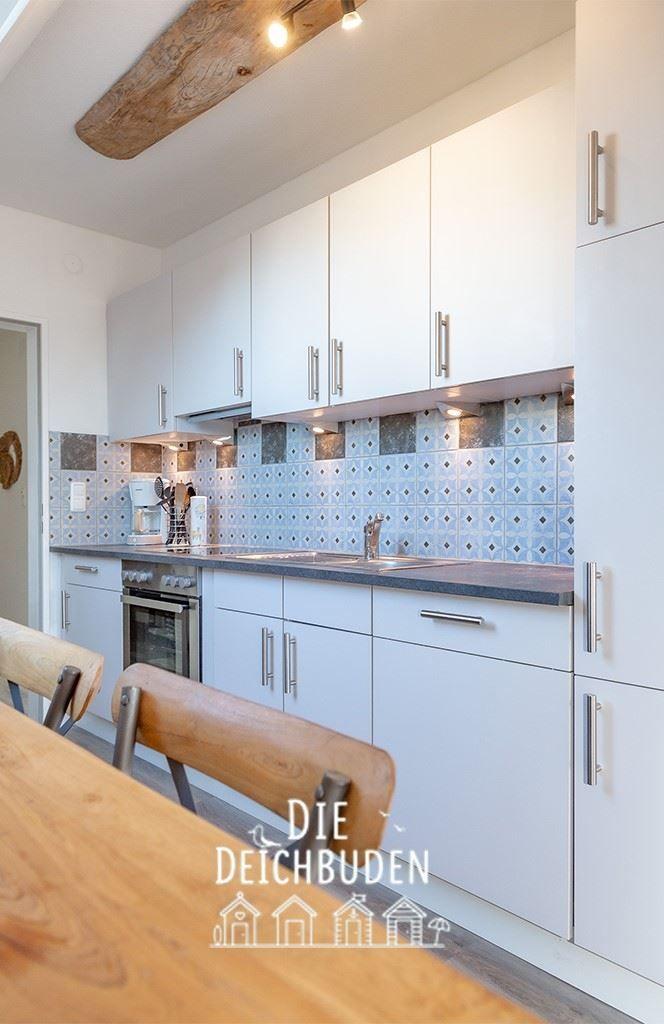 Küche mit weißen Schränken, Mosaikfliesen und Holztisch