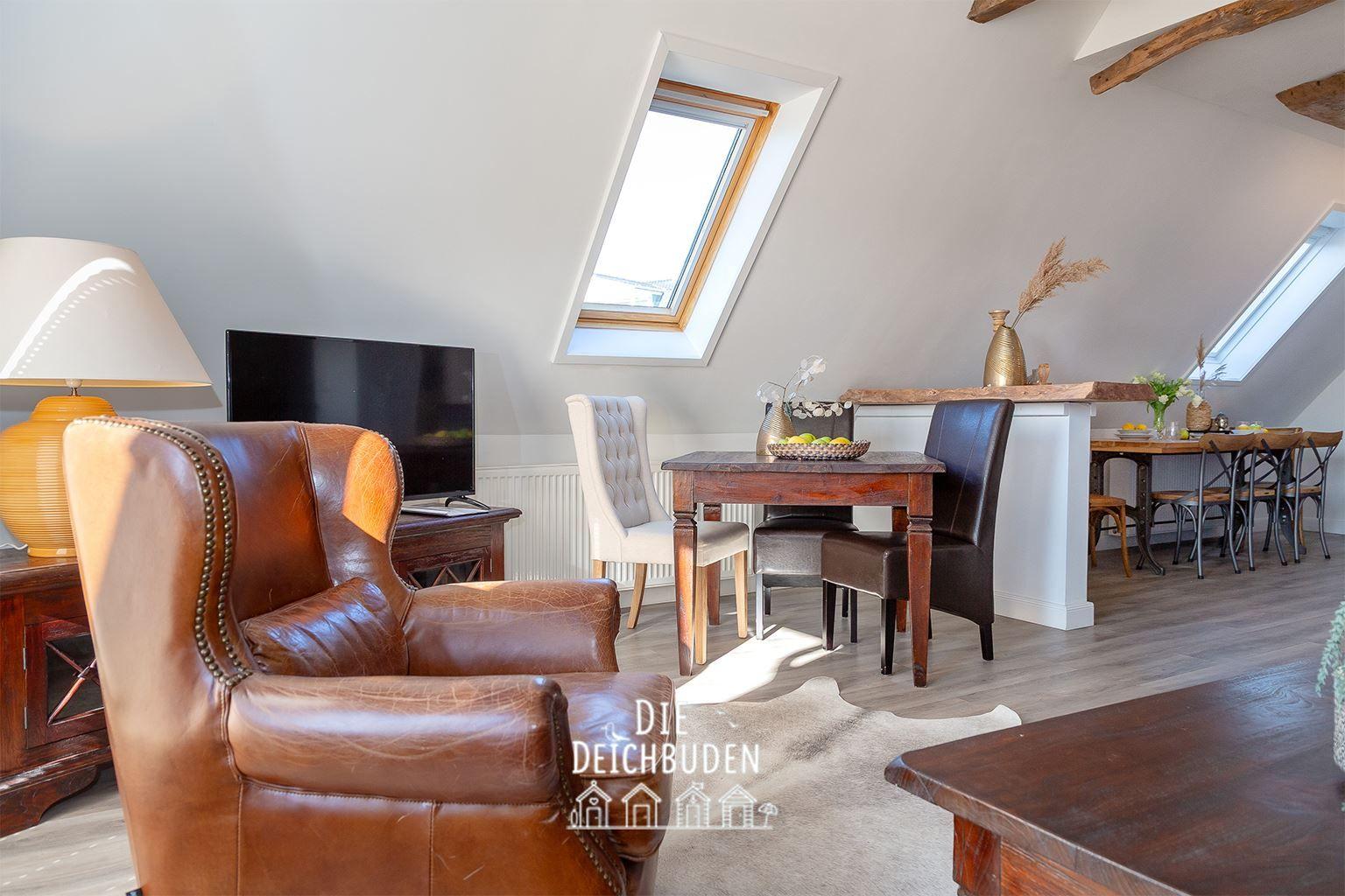 Wohn- und Essbereich mit braunem Ledersofa, Holztisch und Dachfenstern.