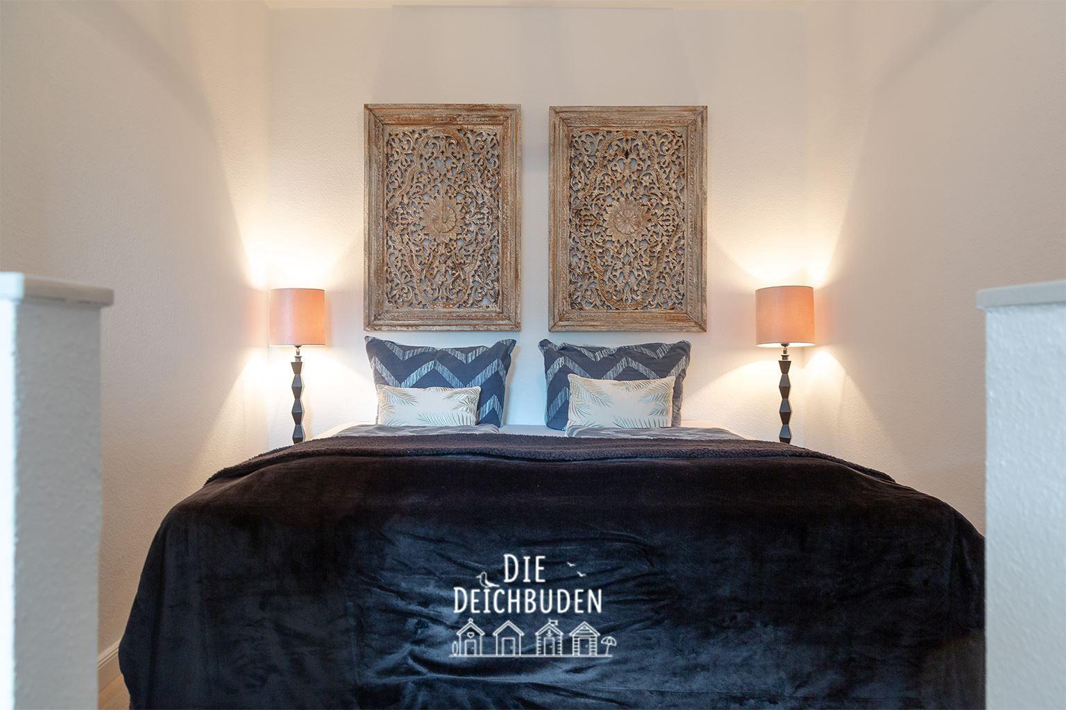 Schlafzimmer mit Bett, zwei Nachttischen und Wanddekoration.