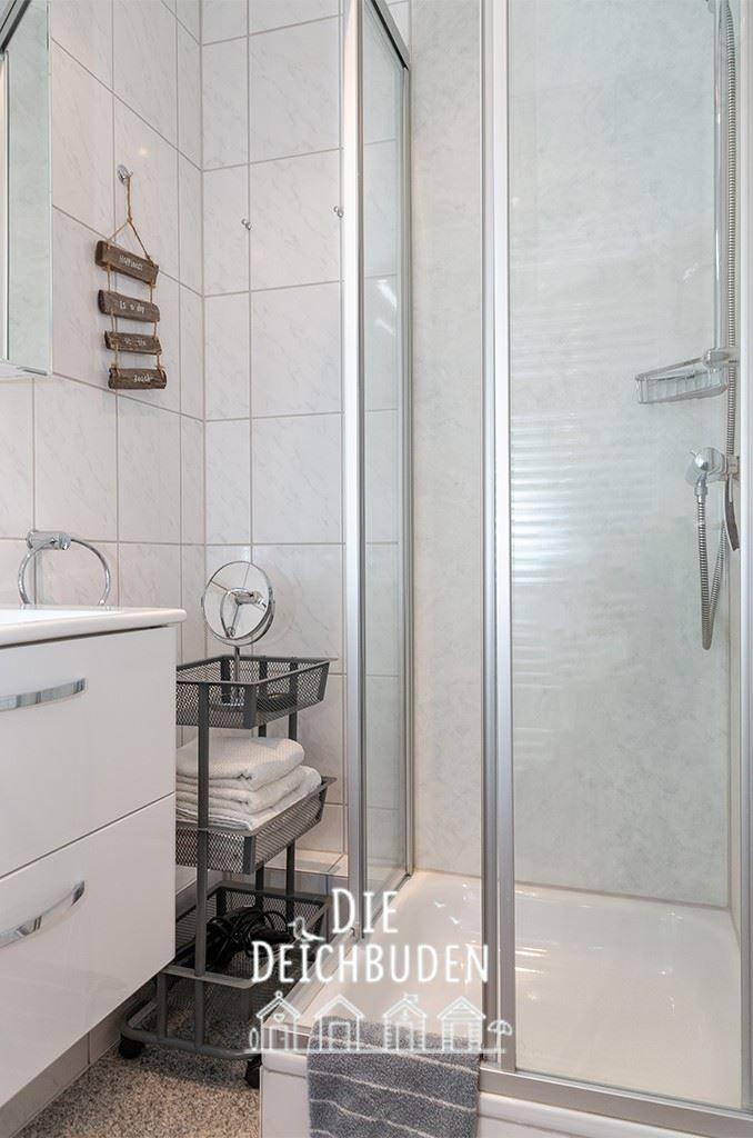 Badezimmer mit Dusche, Waschbecken und Handtuchhalter.