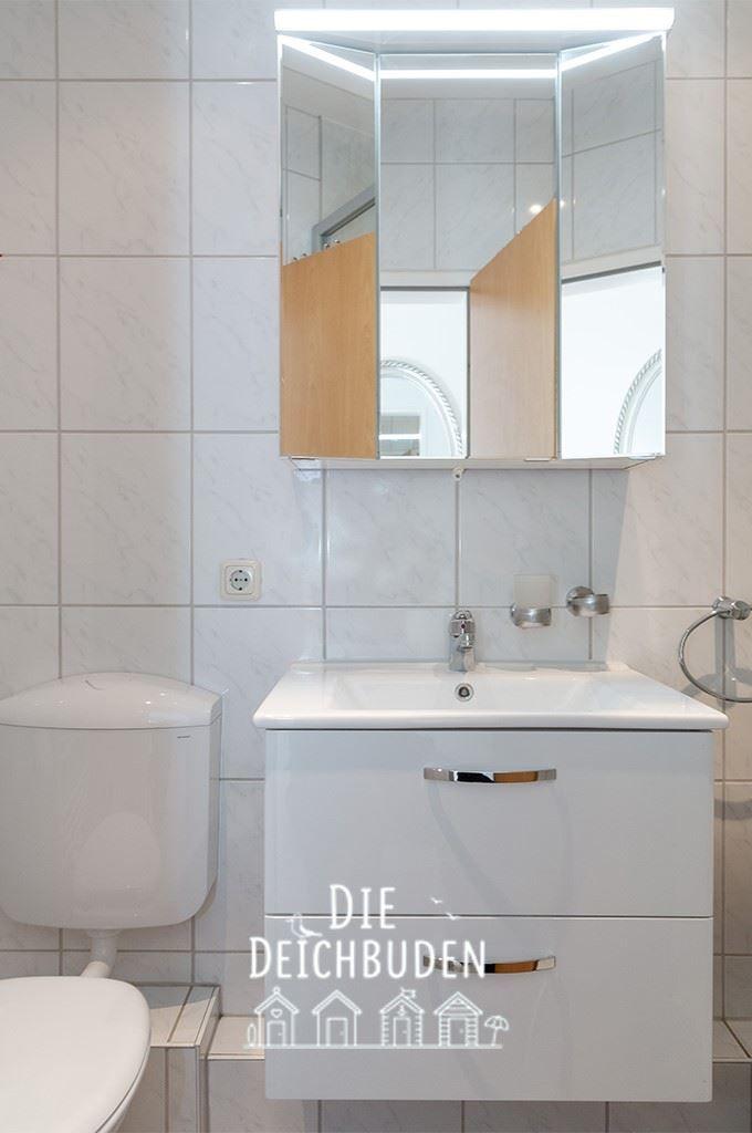 Bad mit Waschbecken, Spiegelschrank und Toilette.