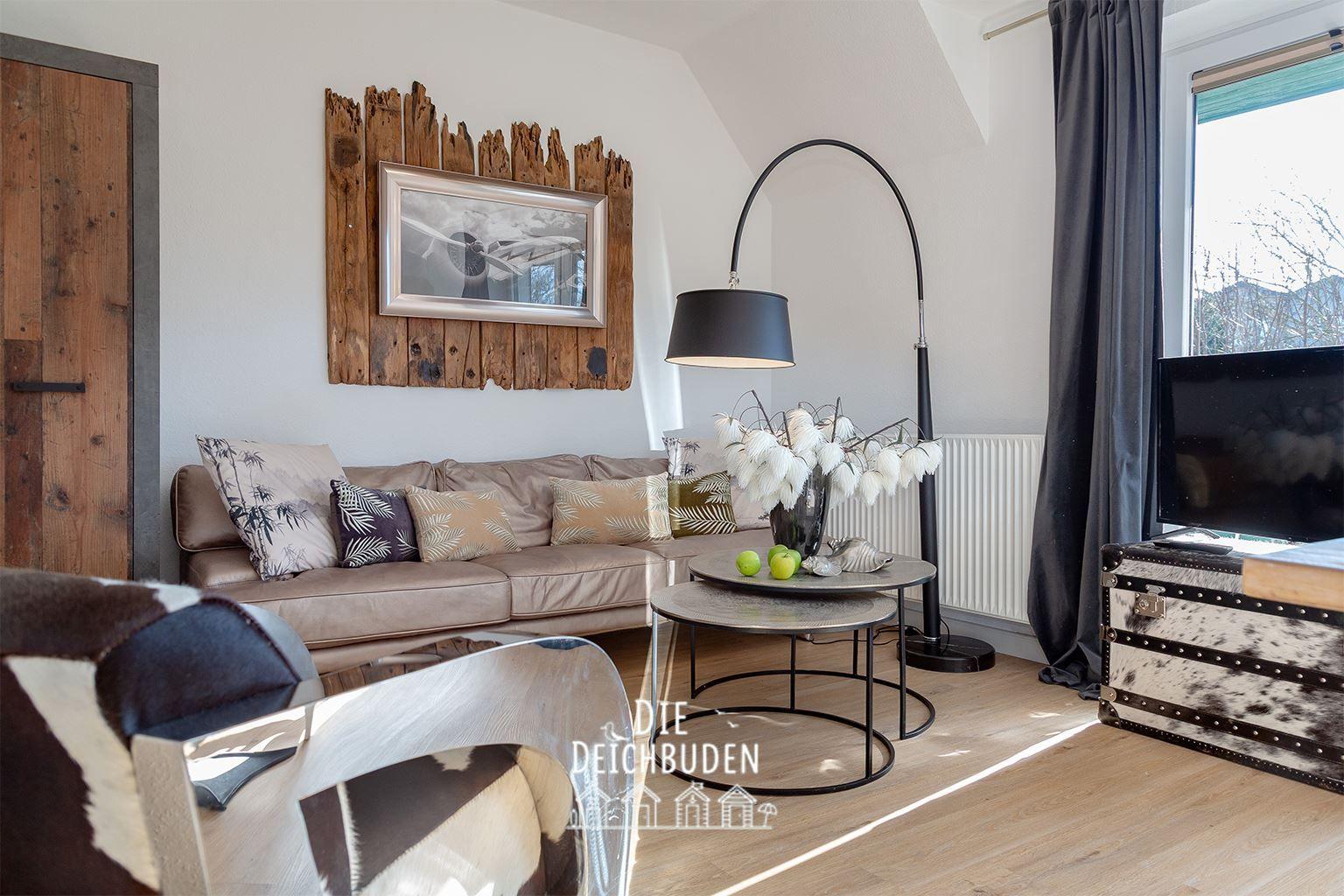 Wohnzimmer mit Sofa, Couchtisch und Stehlampe. Fenster mit Vorhängen und Wandbild.