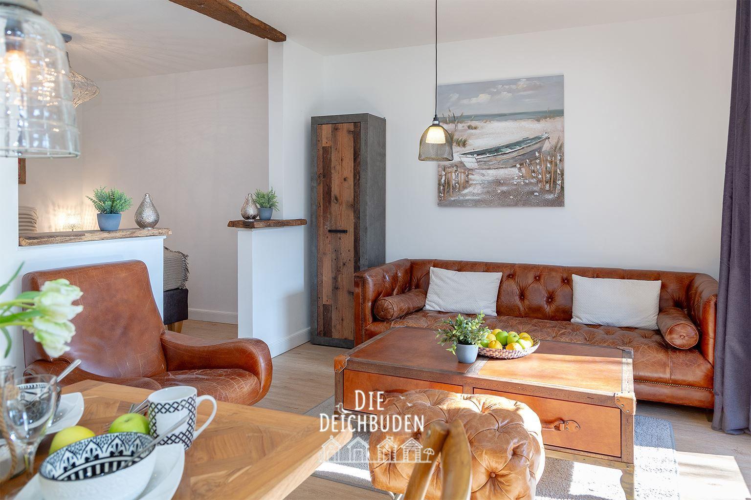 Wohnbereich mit braunem Ledersofa, Holztisch und Wandbild mit Boot.