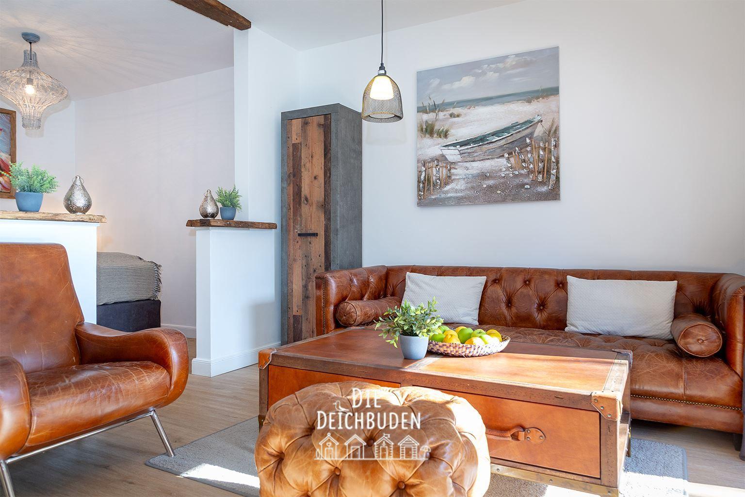 Lichter Raum mit Ledersofa, Holzkonsole und Wandbild. Holzfußboden und Hängelampen.
