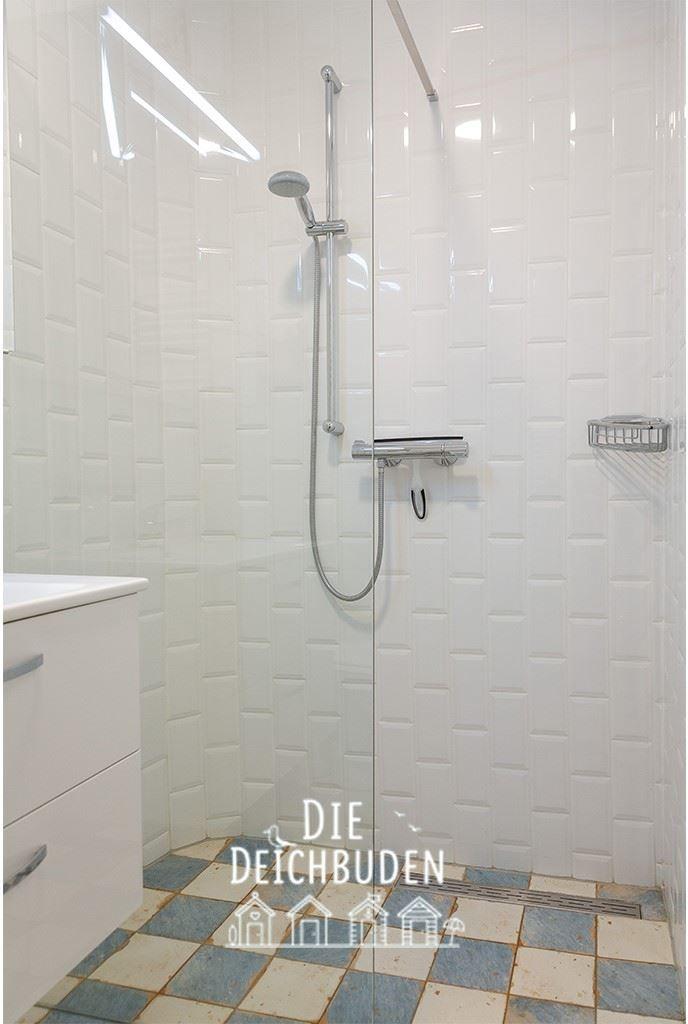 Dusche mit Glaswand, weißen Fliesen und Bodenfliesen in Blau-Weiß