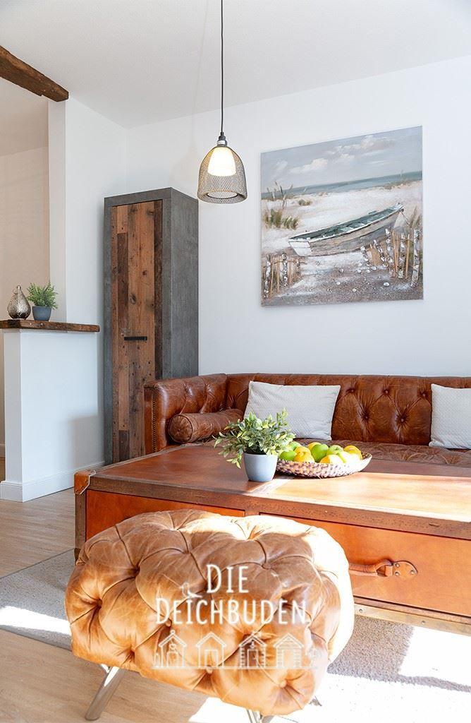 Lounge mit braunem Ledersofa, Holztisch und Wandbild mit Boot.