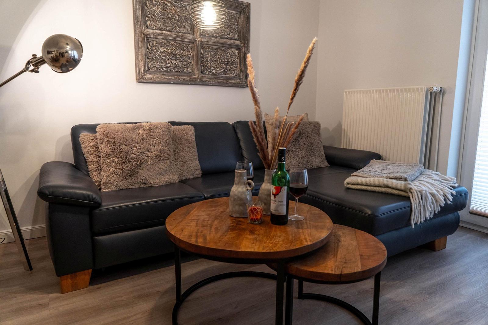 Schwarzes Sofa mit Kissen, Holztisch und Wanddekoration