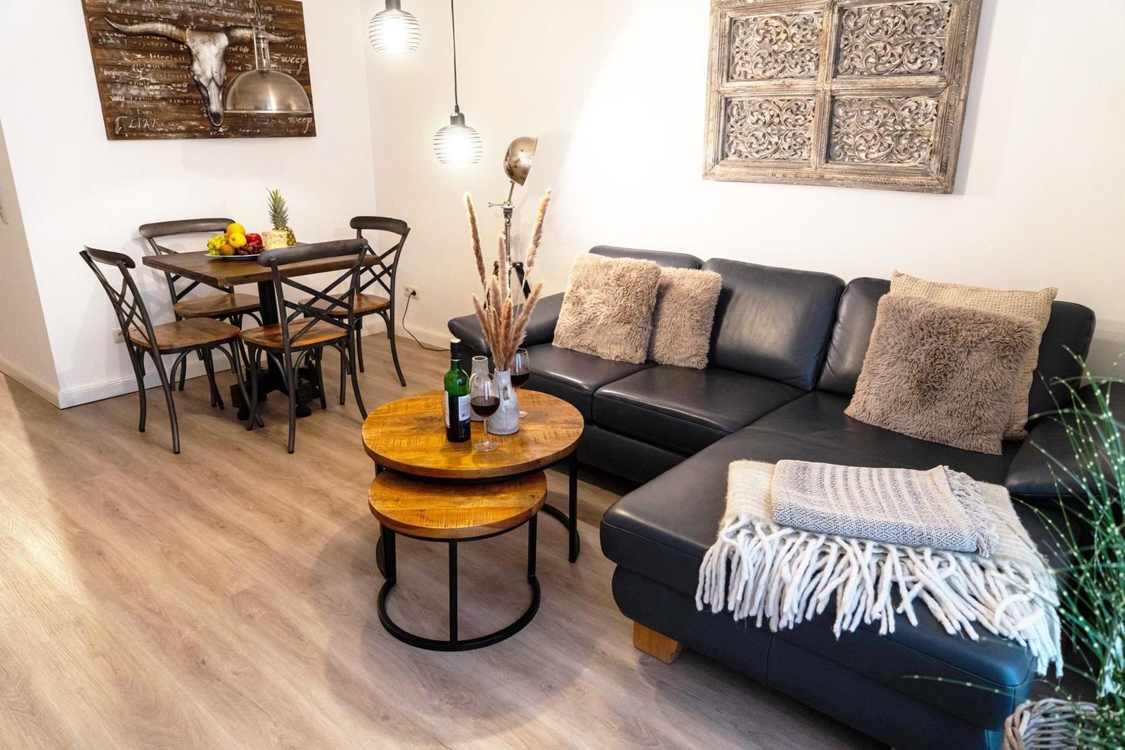 Wohn- und Essbereich mit Sofa, Tisch und Stühlen sowie Wanddekoration.