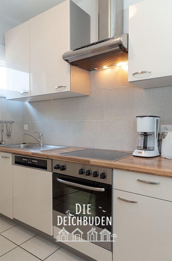 Moderne Küche mit Edelstahlherd, Spüle und Kaffeemaschine.