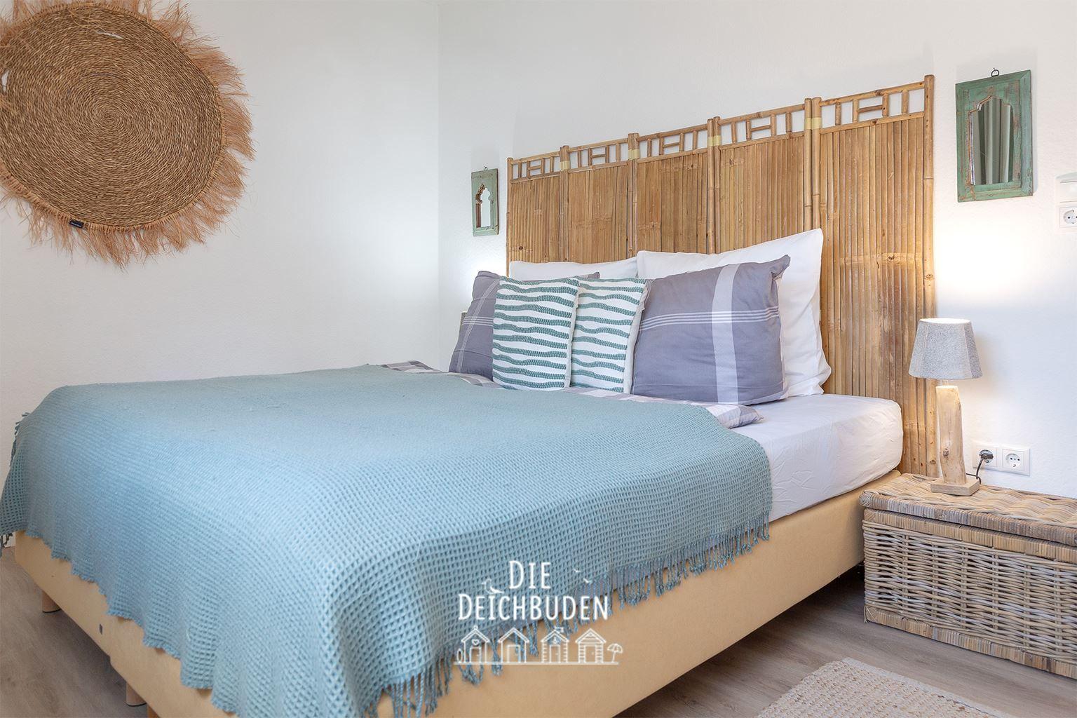 Schlafzimmer mit Bett, Bambus-Schrank und Wicker-Nachttisch.