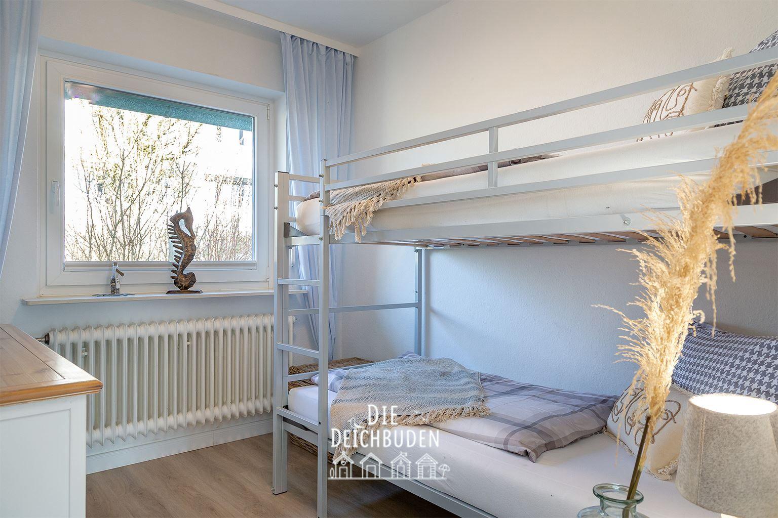 Zimmer mit Doppelstockbett, Fenster und Holzboden.