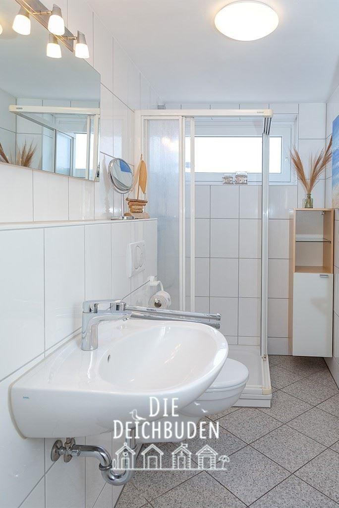 Badezimmer mit Dusche, Waschbecken und Spiegel.