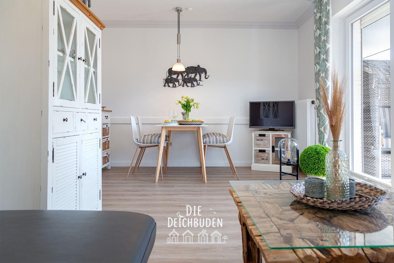 Esszimmer mit Tisch, Stühlen und Schrank. Fernseher und Fenster mit Vorhang.