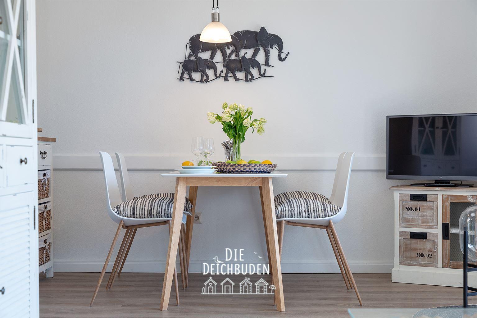 Esstisch mit zwei Stühlen, Wanddekoration und Fernseher