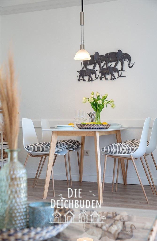 Esstisch mit vier Stühlen, Wanddekoration und Blumen auf dem Tisch.