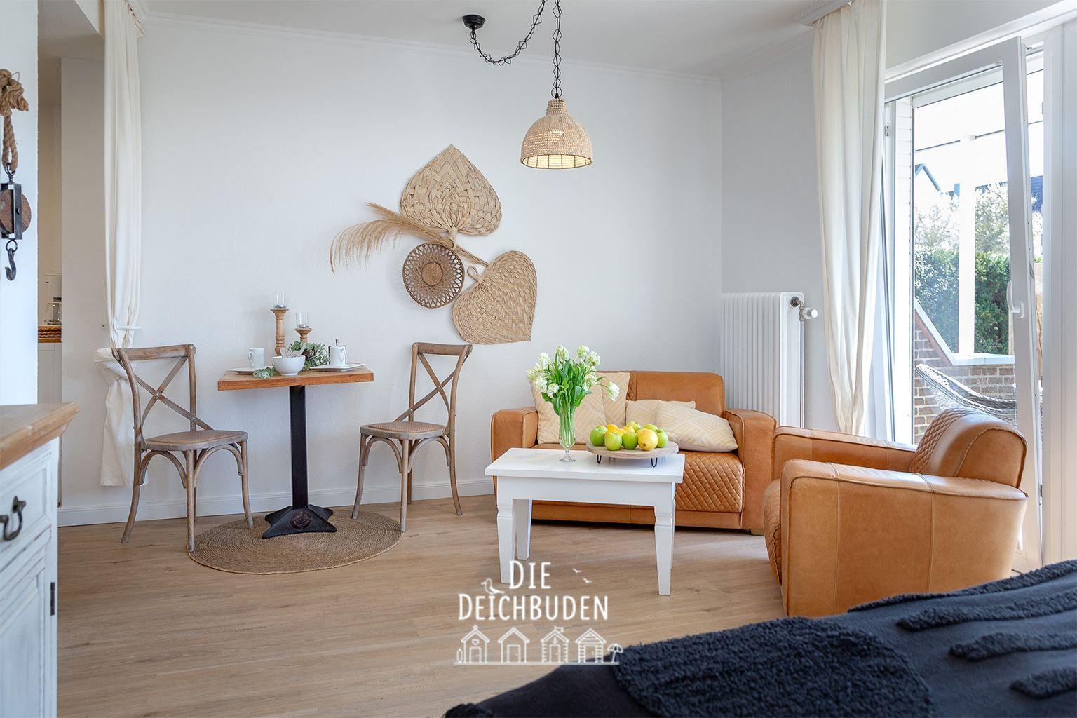 Wohn- und Essbereich mit braunem Sofa, weißem Tisch und Holzstühlen. Wanddekoration und Fenster mit Blick.