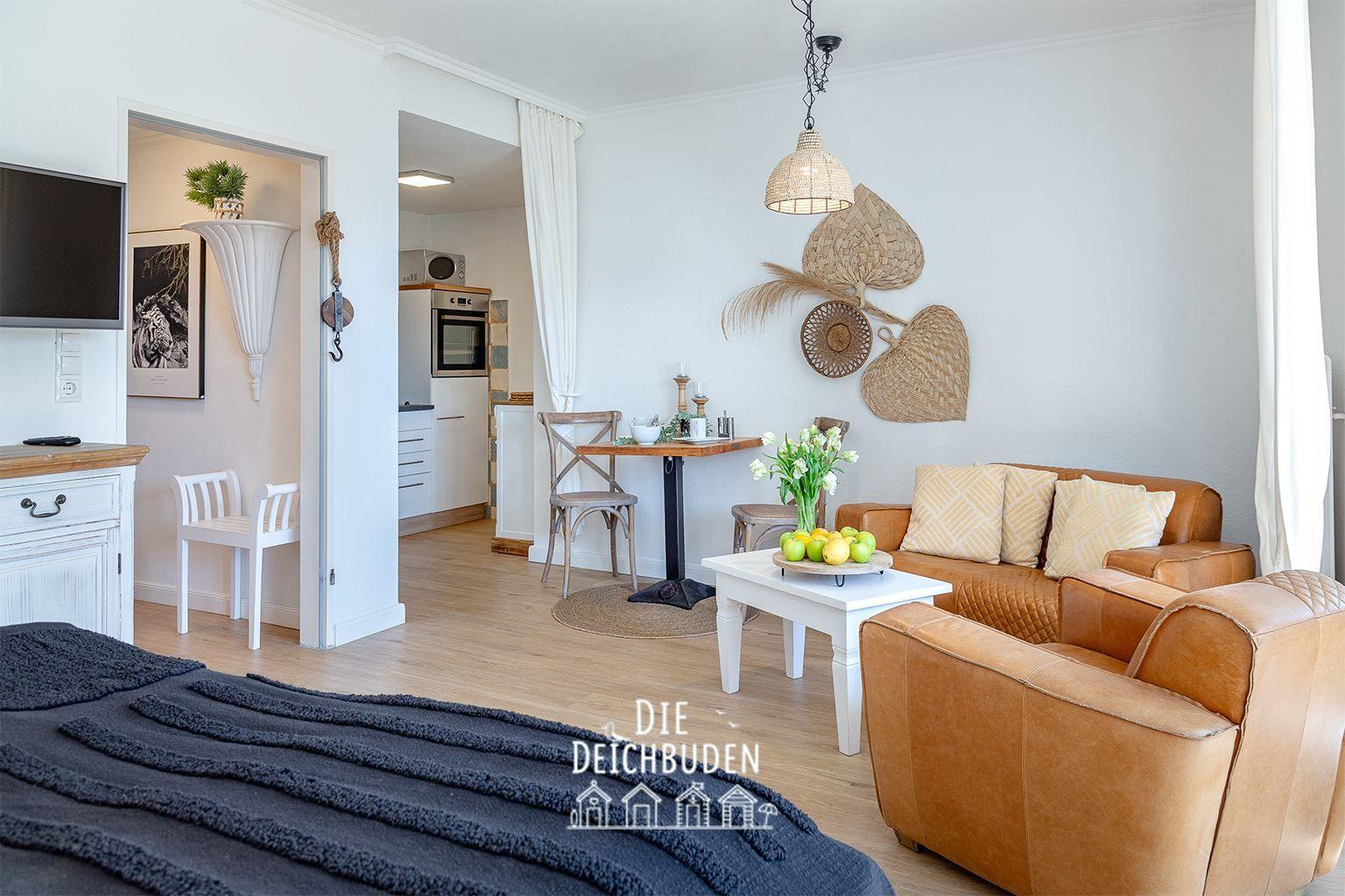 Wohnzimmer mit Ledersofa, Esstisch und Blick in die Küche.