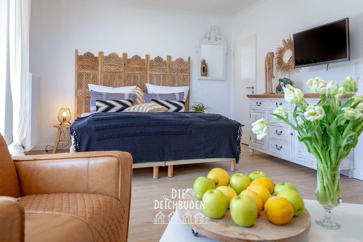 Schlafzimmer mit Holzbett, Fernseher und Früchten auf Tisch.