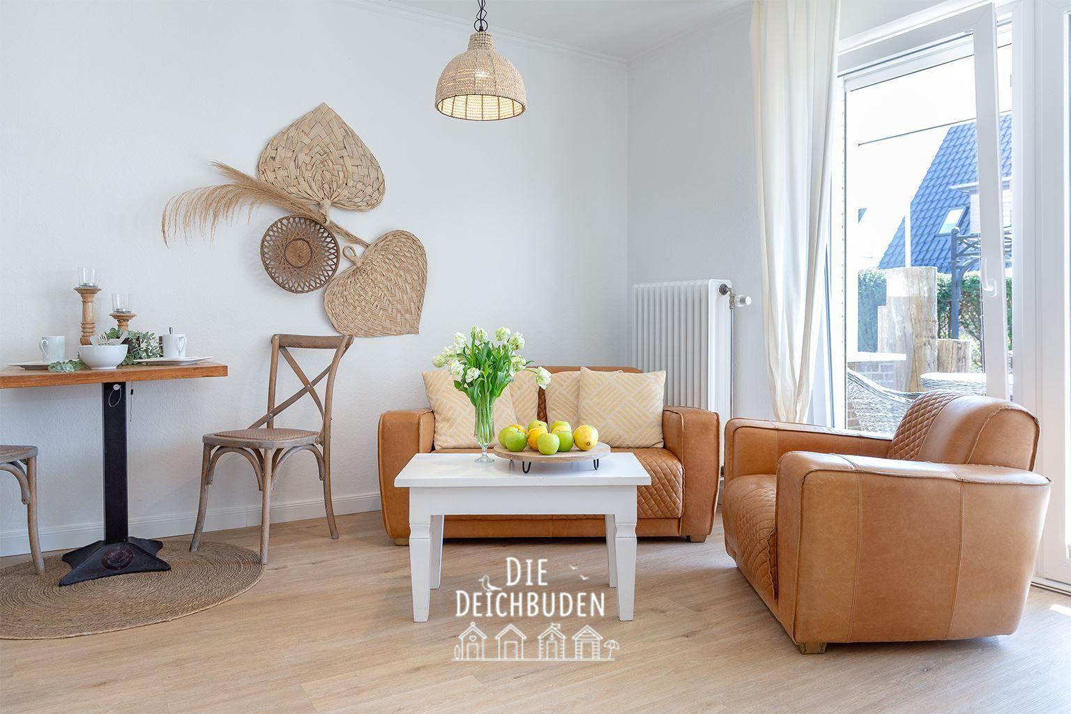 Wohnzimmer mit braunen Ledersofa, weißen Tisch und Holzboden. Wanddekoration und Fenster mit Blick.