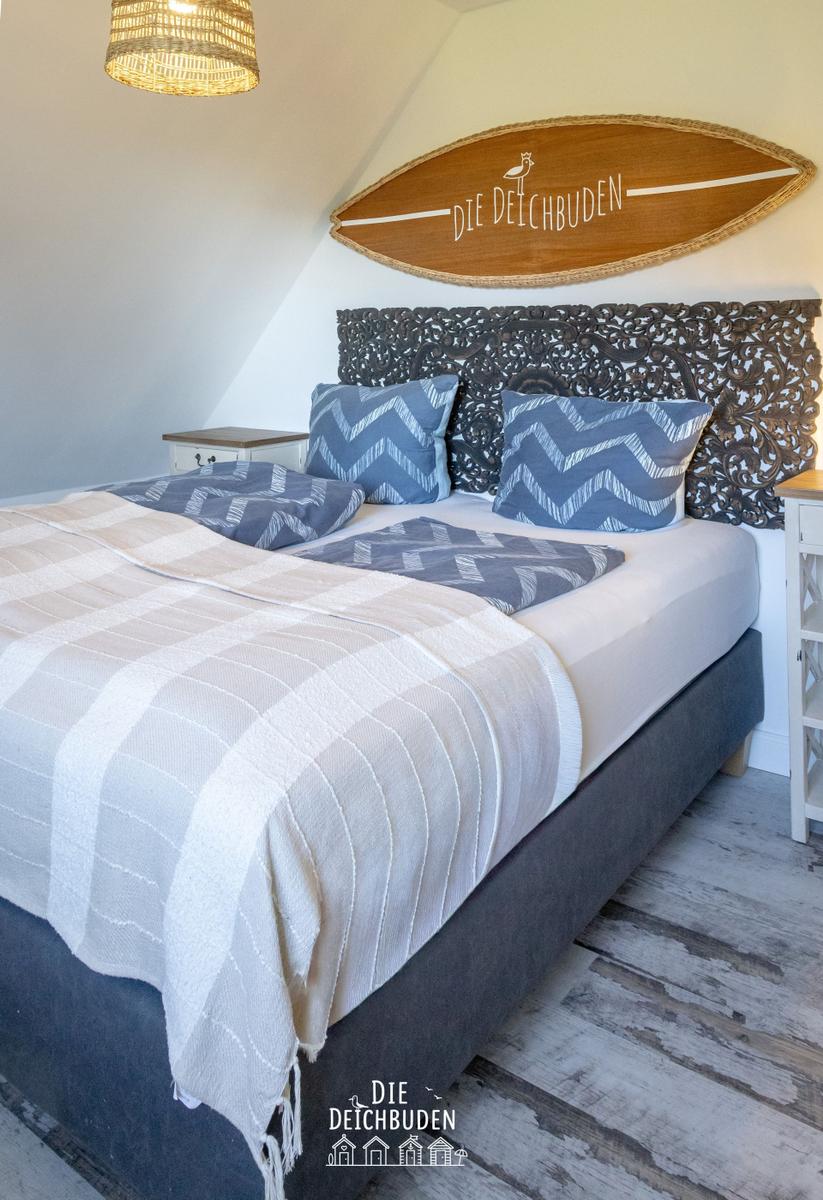 Schlafzimmer mit Bett, Kopfteil und Wanddekoration.