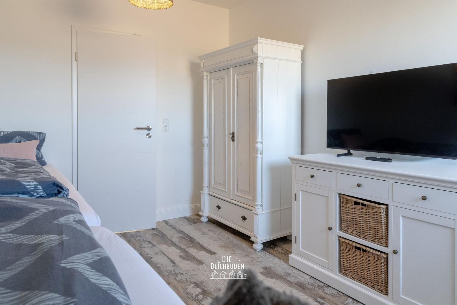 Schlafzimmer mit Bett, Kleiderschrank und TV-Möbel.