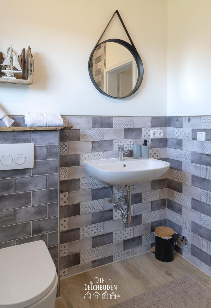 Badezimmer mit Waschbecken, Spiegel und Fliesenwand