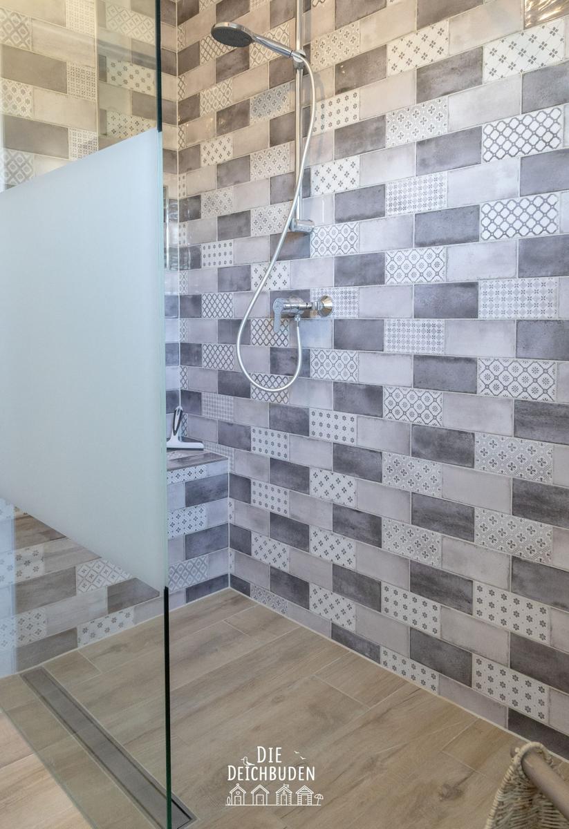 Dusche mit Glaswand und gemusterten Fliesen