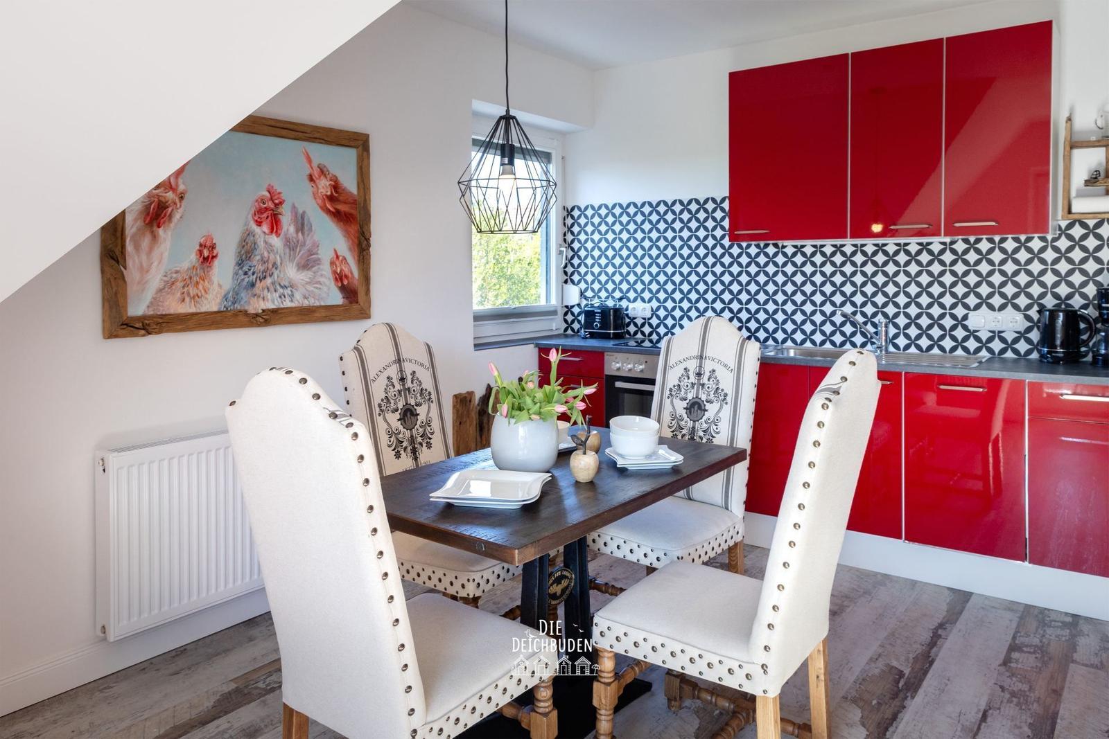 Esszimmer mit roter Küche und Tisch mit Stühlen